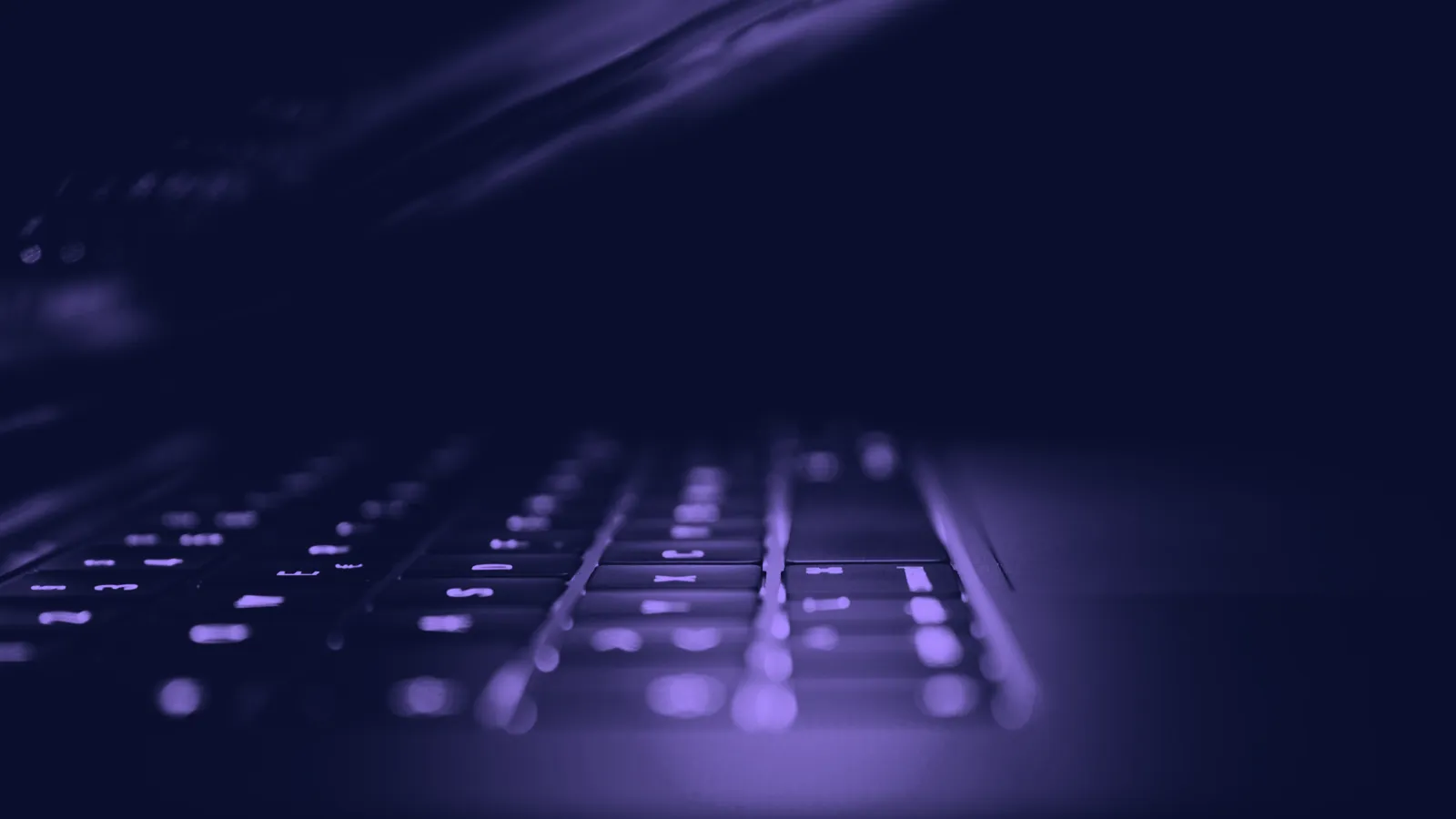 A backlit laptop keyboard in the dark